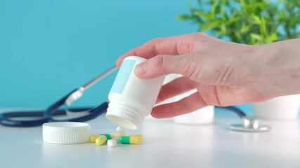 A doctor holds a bunch of pills. There is a stethoscope on a desk, The doctor checks new drugs