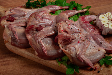 Raw quail meat, on a cutting board, with spices and herbs, top view,