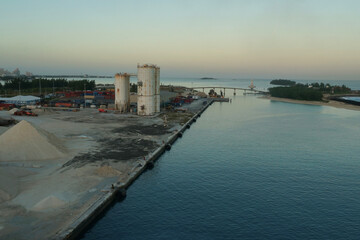 Pier equipped with fenders, industrial storage tanks and piles of stones in port of  Nassau in Bahamas one of the Caribbean island during sunrise. 