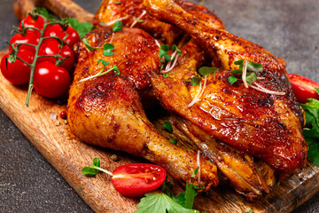 grilled fried chicken legs, served with fresh cherry tomatoes, and herbs, on a wooden chopping board, homemade, no people,