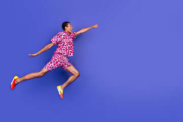 Obraz premium Energetic young man dresses in stylish leopard pink outfit leaps against a bold purple background