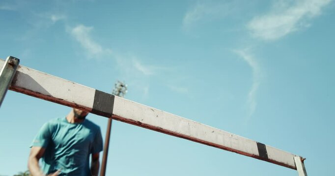 Below, man and jump for hurdle outdoor of fitness competition, run exercise and sports performance. Male athlete, running and obstacle race for cardio training, workout challenge and endurance goals