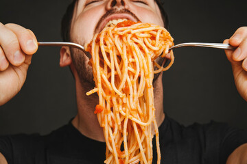 Man enjoying spaghetti with sauce, slurping noodles with joy