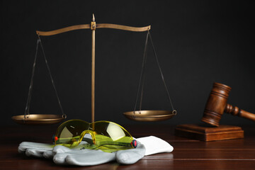 Accident at work concept. Gavel, scales and construction worker's protective gear on wooden table,...