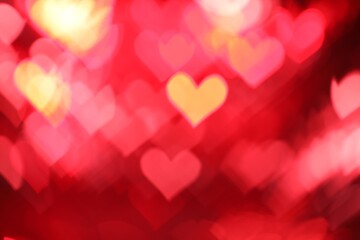 Romantic decor. Blurred view of heart shaped lights on red background, bokeh effect