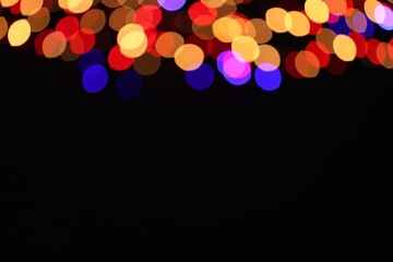 Blurred view of colorful lights on black background, space for text. Bokeh effect