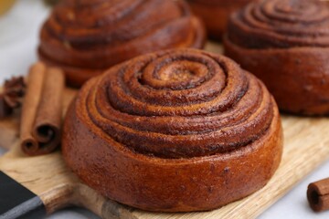 Delicious cinnamon roll buns on light table, closeup
