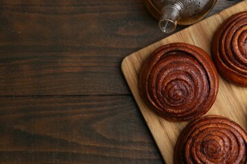 Delicious cinnamon rolls on wooden table, flat lay. Space for text