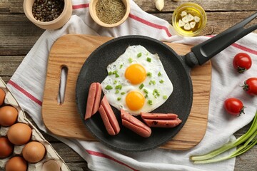 Tasty fried eggs with cut sausages served on wooden table, flat lay