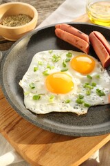 Tasty fried eggs with cut sausages served on table, closeup