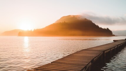 Obraz premium Serene sunset over a tranquil lake with a wooden pier extending towards a misty mountain, creating a peaceful and picturesque landscape.