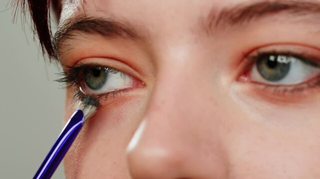 Eye shadow makeup to the upper eyeliner, close-up. Makeup artist applies a bright eye shadow with a makeup brush.Tutorial master class of professional makeup. 