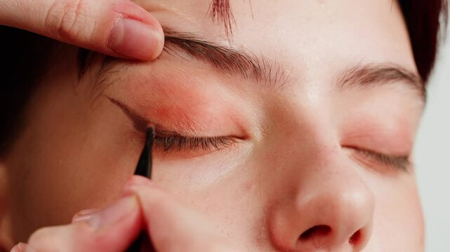 Eye shadow makeup to the upper eyeliner, close-up. Makeup artist applies a bright eye shadow with a makeup brush.Tutorial master class of professional makeup. 