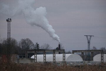 smoke coming from tall chimney in industrial district.