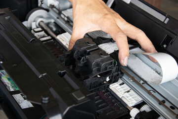 Top view of technician inspecting and repairing printer.