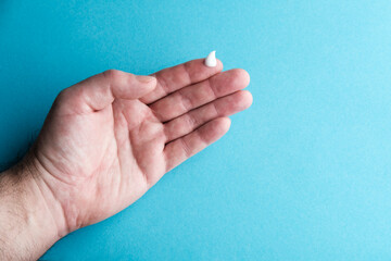 Man holding moisturizing cream in hand on blue background