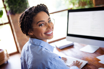 Confident young businesswoman using computer in bright office workspace filled with natural light