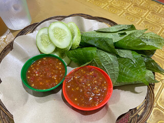Indonesian traditional sambal, Cucumber slices are presented alongside two bowls of spicy dipping...