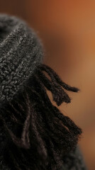 Close-up of dark grey knitted fabric with tassels, autumnal background, texture detail for textile design