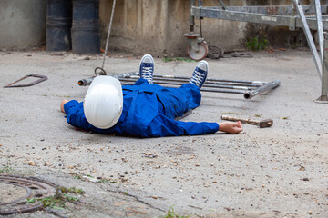 Construction worker lying unconscious on the ground after a workplace accident with safety helmet on