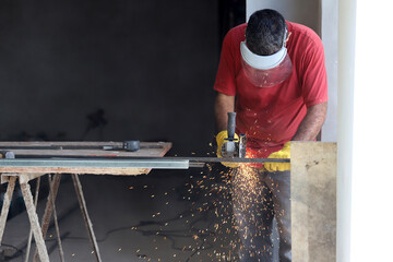 
Blacksmith cutting iron rod with grinder that produces sparks. Background with copy space