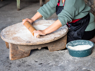 woman rolls out dough with wooden rolling pin