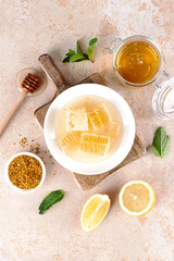 Acacia honey, honeycomb, lemon and mint leaves on beige background