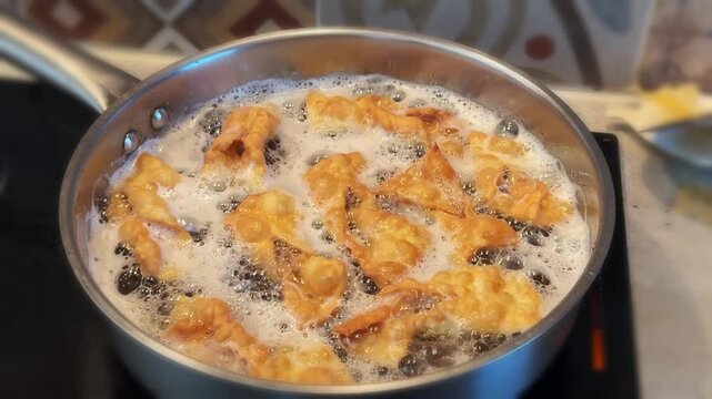 Traditional Polish sweet crispy biscuits called Faworki being dusted with powder sugar on a kitchen countertop