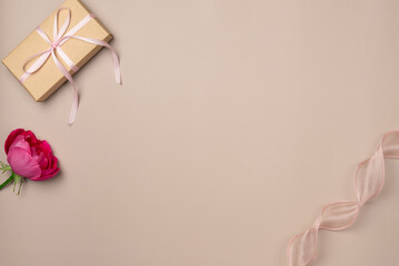 Gift box, rose with ribbon on beige background. Flat lay, top view. Copy space