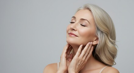Fototapeta premium Attractive mature woman with silver gray hair and smooth skin touches her neck. Suitable for beauty, aging gracefully, skincare, wellness, and lifestyle content