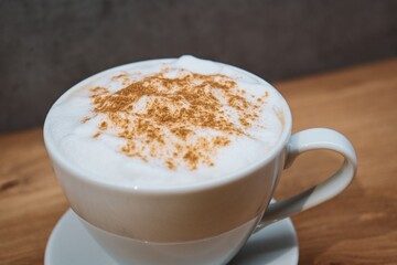 Cup of cappuccino with cinnamon on a wooden table