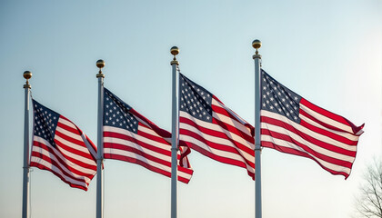 Four American flags waving on flagpoles against clear sky