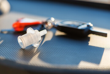 Mouthpiece used for blowing into breathalyzers during police checks next to vehicle keys.