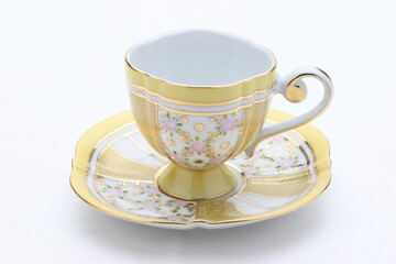 Elegant yellow teacup and saucer with gold and floral decorations, ready for a warm beverage