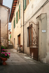 Obraz premium An old typical alley of a town in Tuscany in the region of Firenzuola, in Florence, Italy. Typical rural lifestyle scene with a flower pot and a classic bicycle with basket