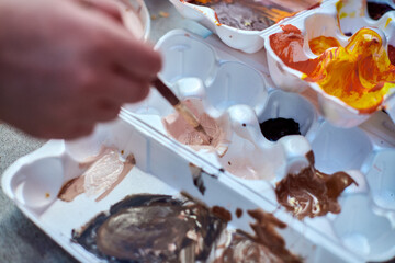 Hand mixing colors on palettes in daylight