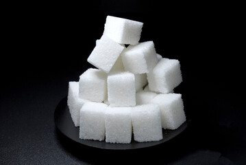 pressed sugar in the form of white cubes laid out with a pile on a black background