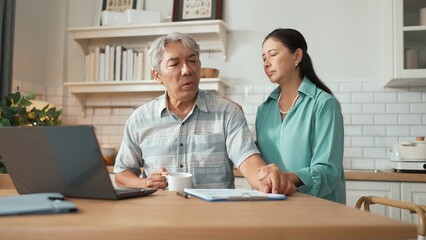 Obraz premium Grandmother holding hot coffee cup and encouraging stressful project manager disappointing about deceasing sales or working problem while old man with casual cloth pointing at laptop screen. Myrmidon.