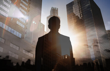 A businessman looks out over the city skyline at sunset. Man silhouette facing  New York City,...