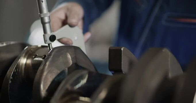 Engineer measuring crankshaft with a micrometer, Precision measurement of a crankshaft with a micrometer