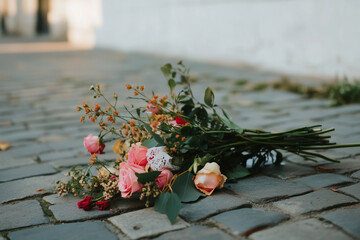 Bouquet of flowers is laying on a cobblestone street
