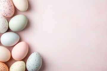 A border of Easter eggs in pastel colors on a pink background. There is an empty space for text on the right, a flat lay.