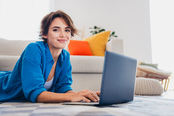Photo of adorable cheerful girl reading news on device spending free time weekend at home indoors