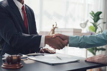 Successful Deal Closed: Two individuals, one in a suit, shake hands across a desk, symbolizing a...