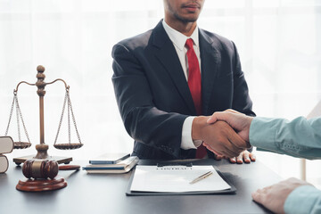 Legal Handshake: A lawyer in a sharp suit extends a firm handshake to a client, signifying trust and partnership, with a scale of justice and a gavel in the background.  