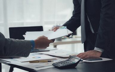 Business Deal Close Up: Two businesspeople exchange important documents, signifying a successful...