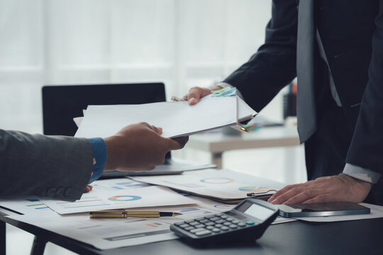 Business Deal: Two businessmen, hands close-up, exchange documents, showcasing professionalism and a collaborative environment in a professional setting. - Powered by Adobe