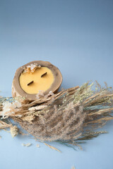 natural wax candle in a wooden cut on a blue background