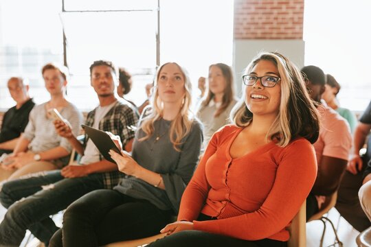 A diverse group of men and women, including a woman of South Asian ethnicity, attentively listening in a seminar. Community group of men and women are engaged in the seminar. Community group seminar.