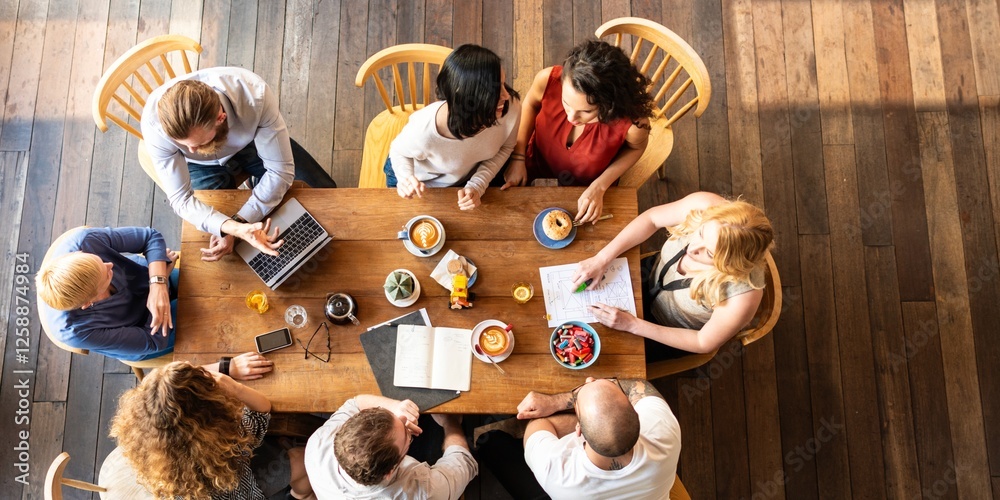 Aufkleber Top view of a diverse group of people having a meeting around a wooden table with laptops and documents. Collaborative team discussion in a office. Casual startup business team working at a cafe.